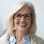 Smiling woman with glasses and blonde hair.