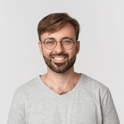 Man with glasses smiling in gray shirt.