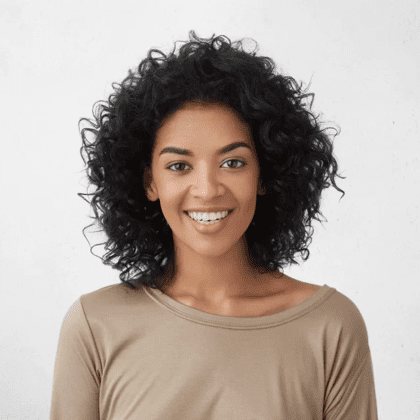 Smiling person with curly hair and beige top.