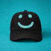 Black baseball cap with teal smiley face