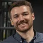 Smiling bearded man by bookshelf